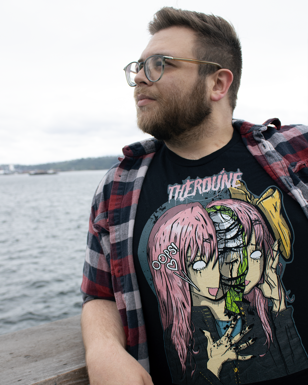 Person on pier looking into ocean wearing black shirt with anime stylized woman, head splitting open revealing a crying woman inside. Speech text saying "Oops!" with Therdune logo on top in pink.