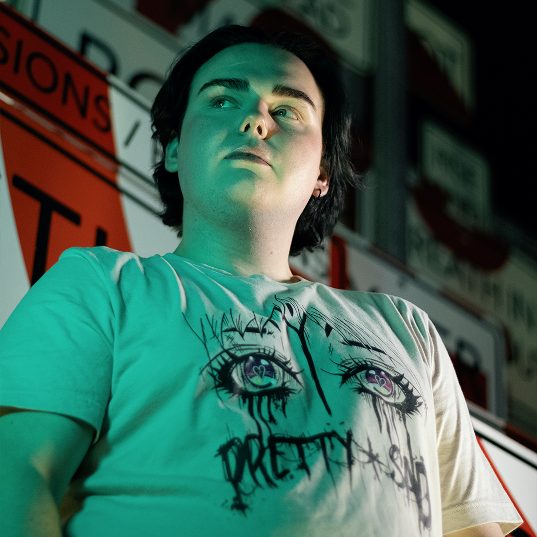 Person wearing a white t-shirt with a graphic print of stylized eyes and the text 'Pretty & Sad' on the front.