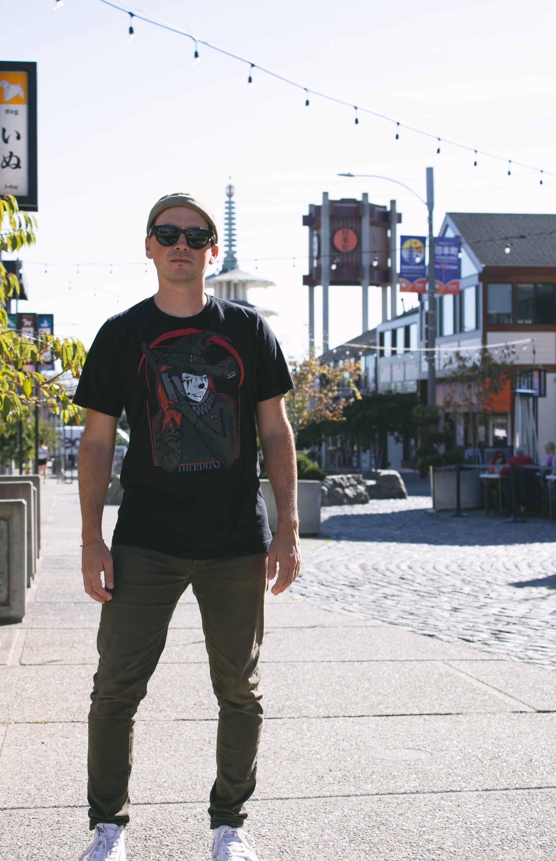 Person wearing black shirt with a graphic of a witch in clown makeup, holding a tarot card in front of a red crescent moon. "Therdune" logo on bottom of graphic.
